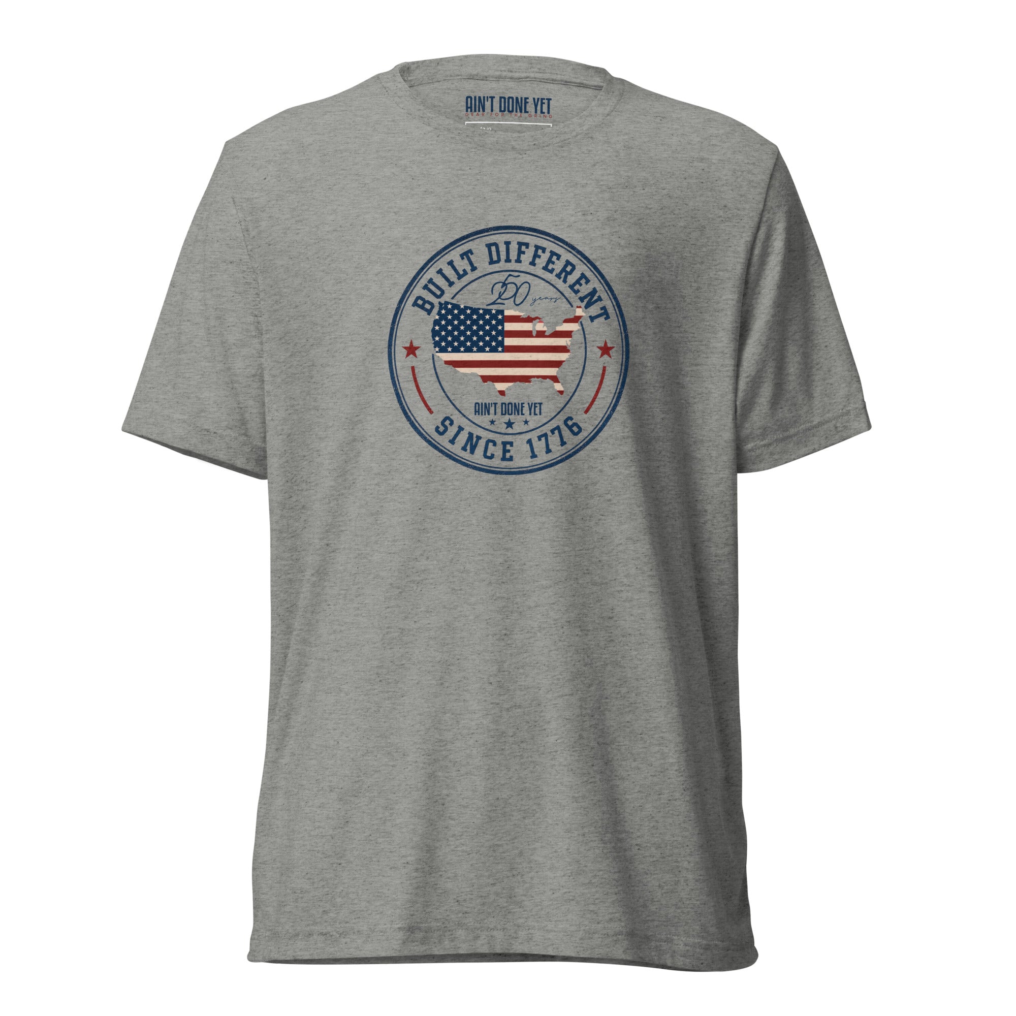 Built Different America 250 athletic grey tri-blend t-shirt featuring patriotic circular emblem with American flag and 1776 design.