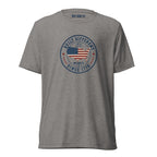 Built Different America 250 grey tri-blend t-shirt featuring patriotic circular emblem with American flag and 1776 design.