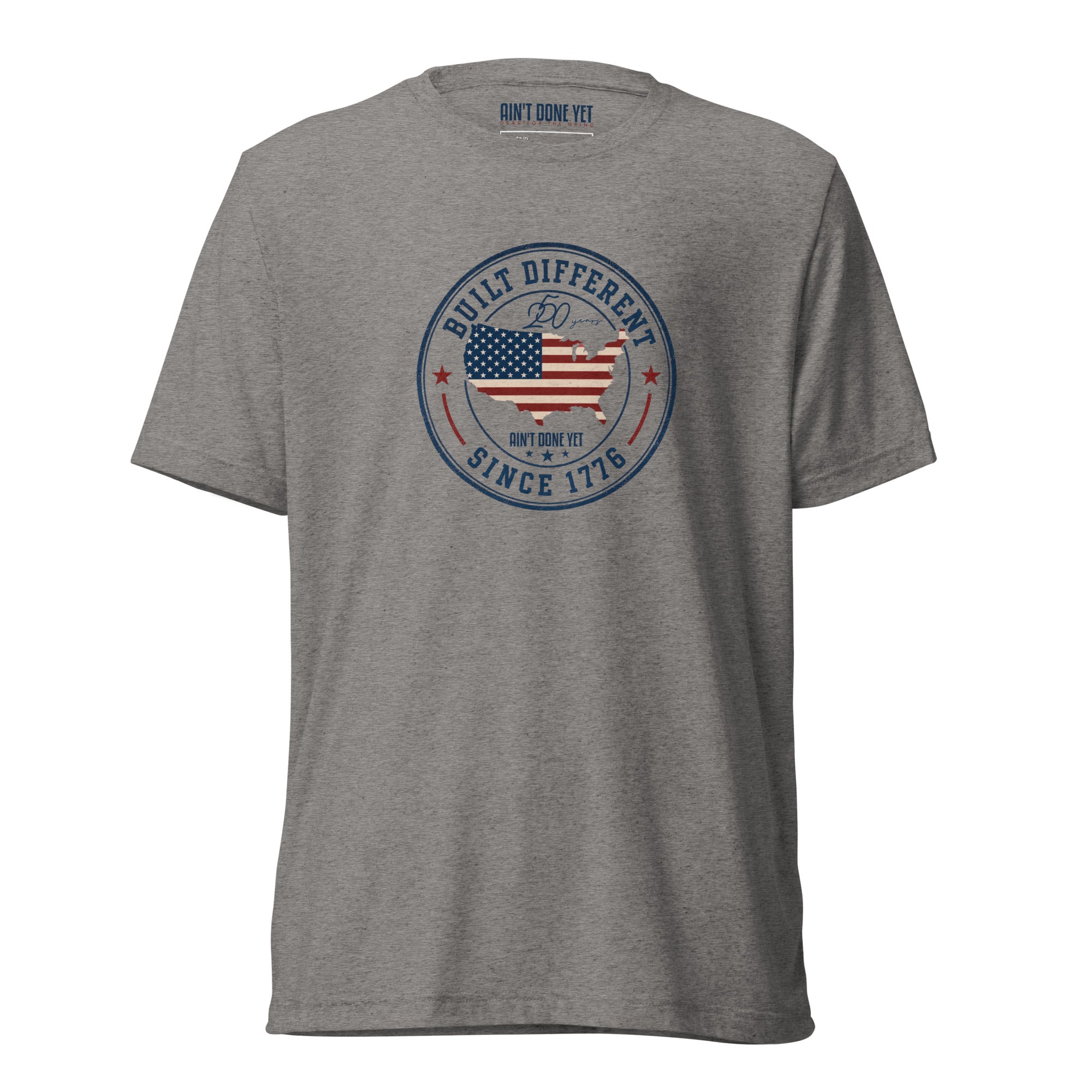 Built Different America 250 grey tri-blend t-shirt featuring patriotic circular emblem with American flag and 1776 design.