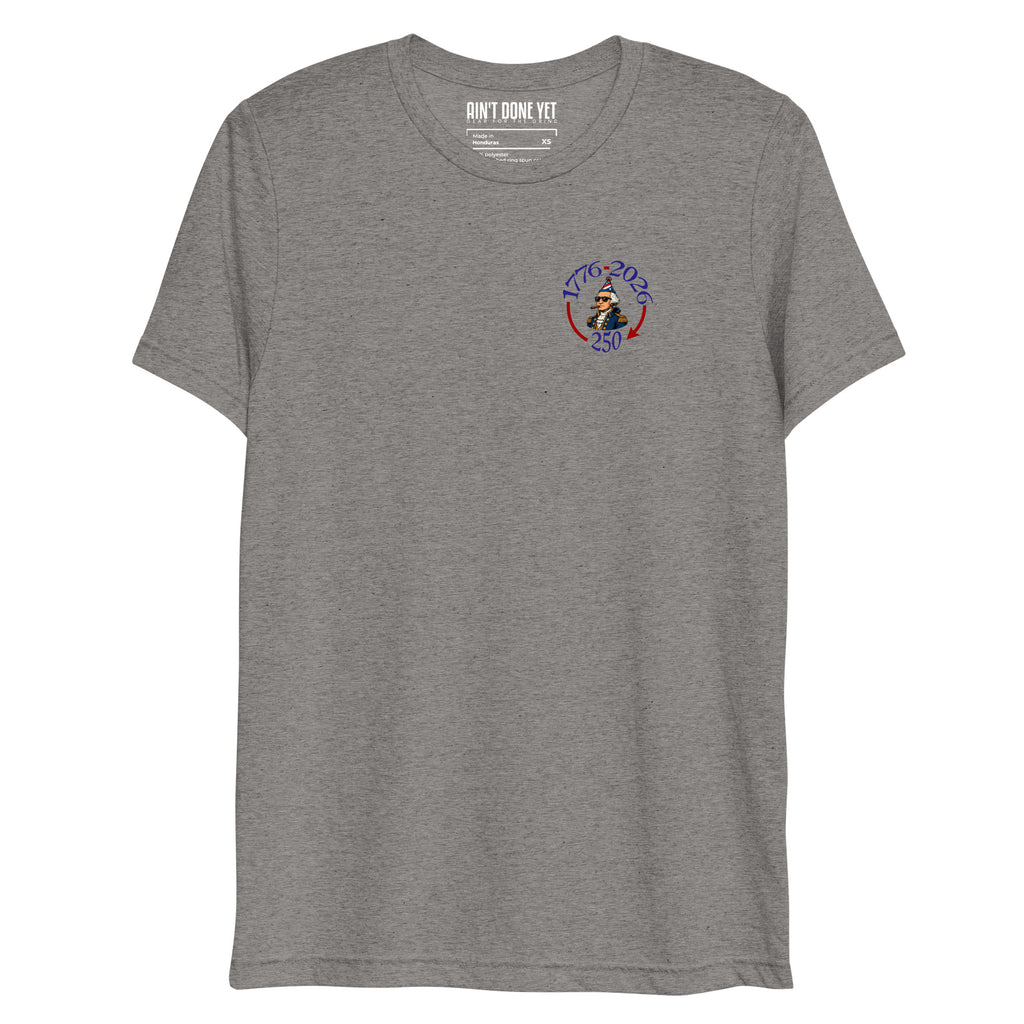 Still Partying America 250 grey t-shirt featuring George Washington wearing a birthday hat and sunglasses with a cigar, commemorating America's 250th anniversary.