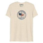 Built Different America 250 oatmeal tri-blend t-shirt featuring patriotic circular emblem with American flag and 1776 design.