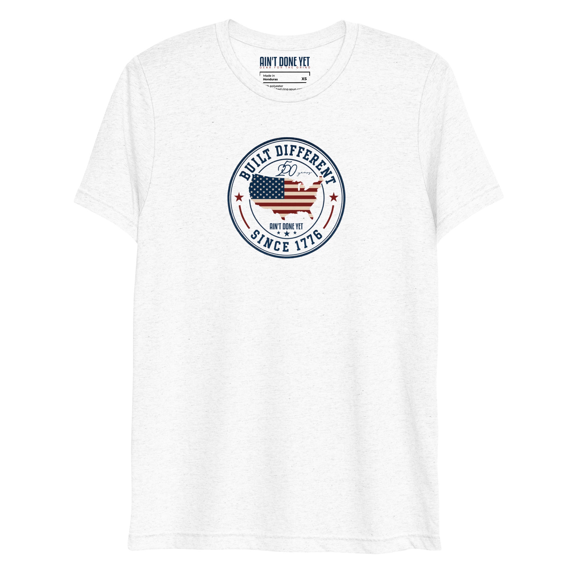 Built Different America 250 white tri-blend t-shirt featuring patriotic circular emblem with American flag and 1776 design.
