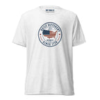 Built Different America 250 white tri-blend t-shirt featuring patriotic circular emblem with American flag and 1776 design.
