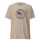 Built Different America 250 tan tri-blend t-shirt featuring patriotic circular emblem with American flag and 1776 design.