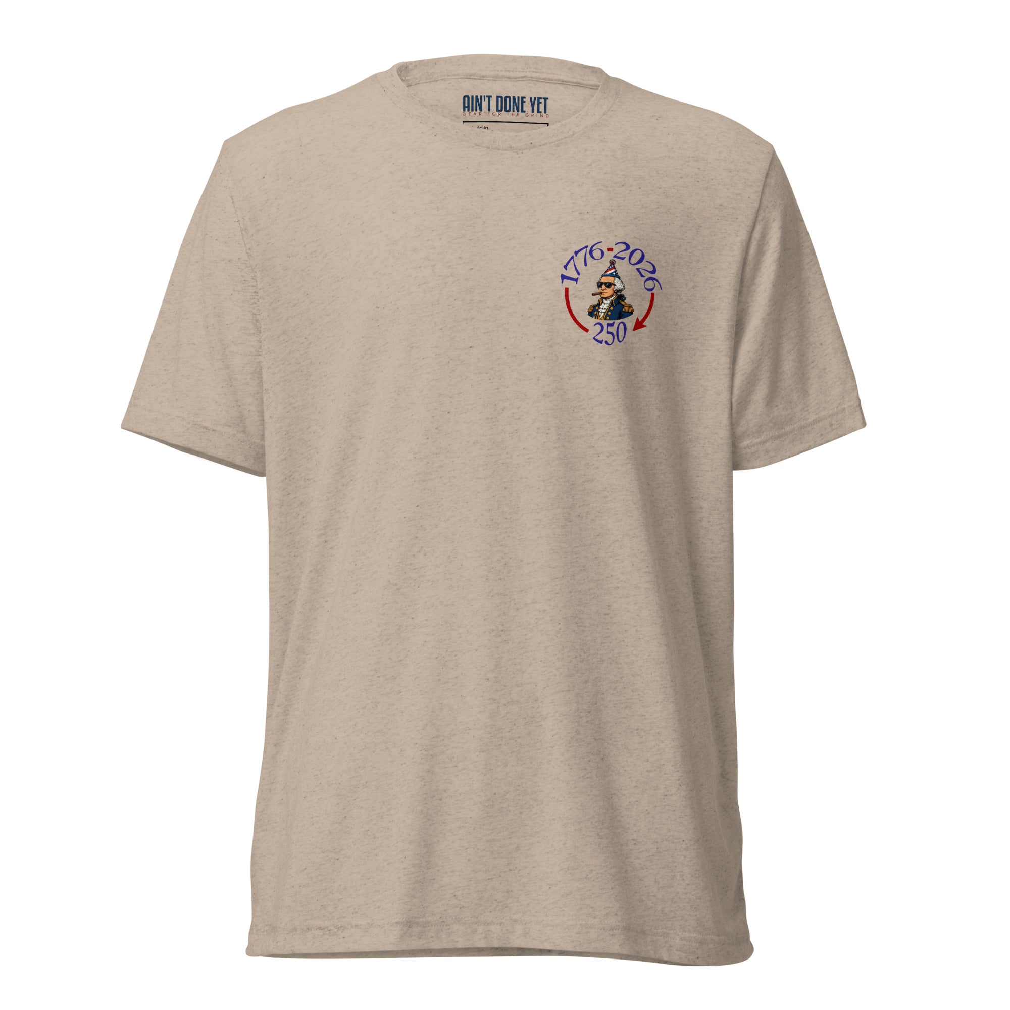 Still Partying America 250 tan t-shirt featuring George Washington wearing a birthday hat and sunglasses with a cigar, commemorating America's 250th anniversary.