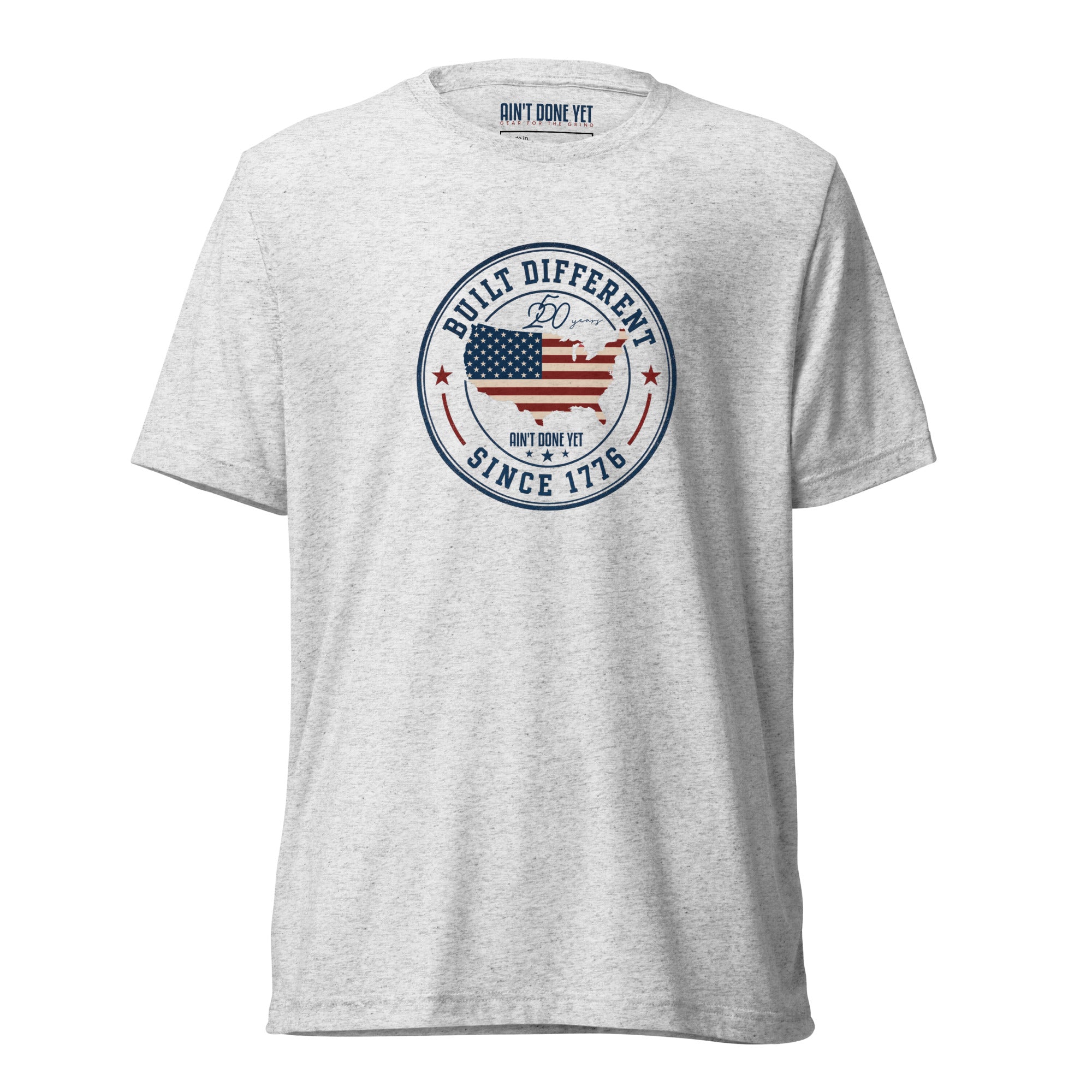 Built Different America 250 white fleck tri-blend t-shirt featuring patriotic circular emblem with American flag and 1776 design.